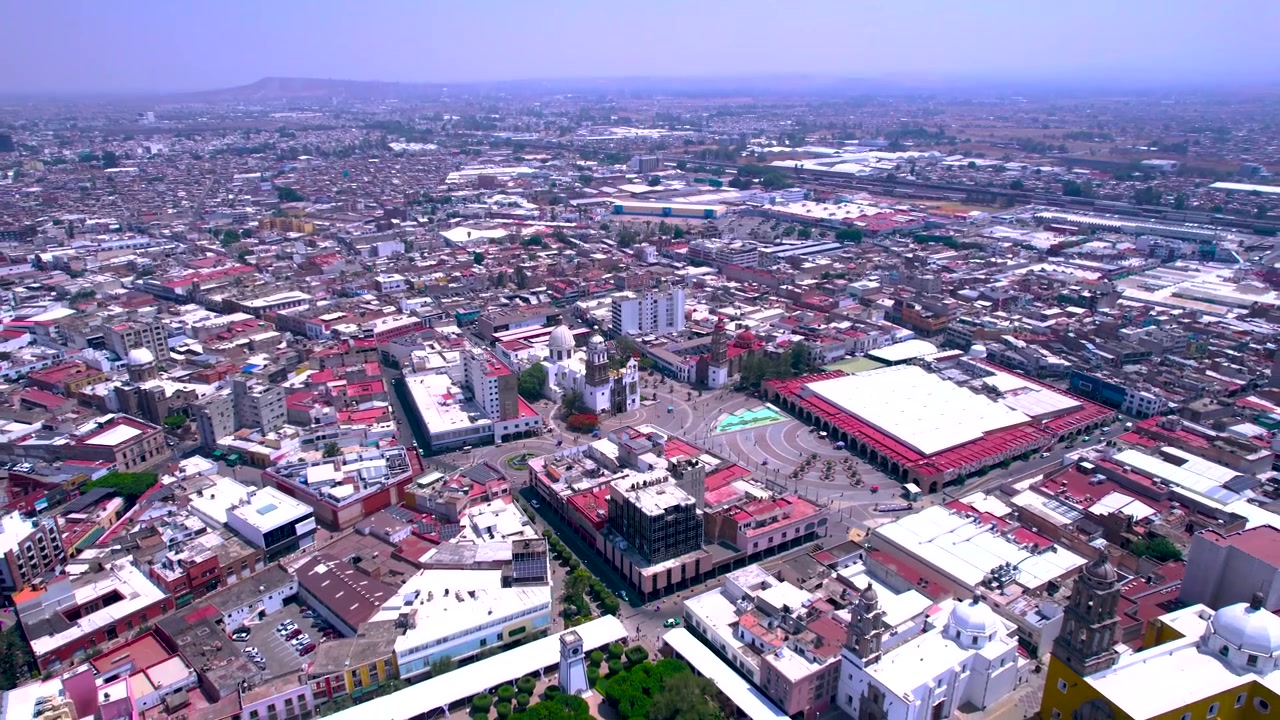 Vista aérea cinematográfica de drone sobre o centro de Irapuato, Guanajuato, revelando arquitetura histórica, ruas urbanas, áreas comerciais e a densa paisagem metropolitana da cidade