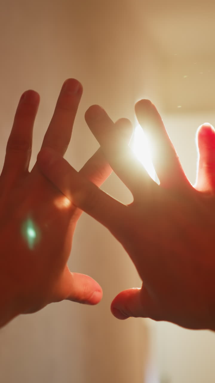 de la persona en casa, mirando a través de los dedos en los brillantes rayos del sol, creando una atmósfera interior acogedora e íntima