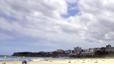 time lapse: south bondi beach with people moving across the sand as thick white clouds shift in the sky