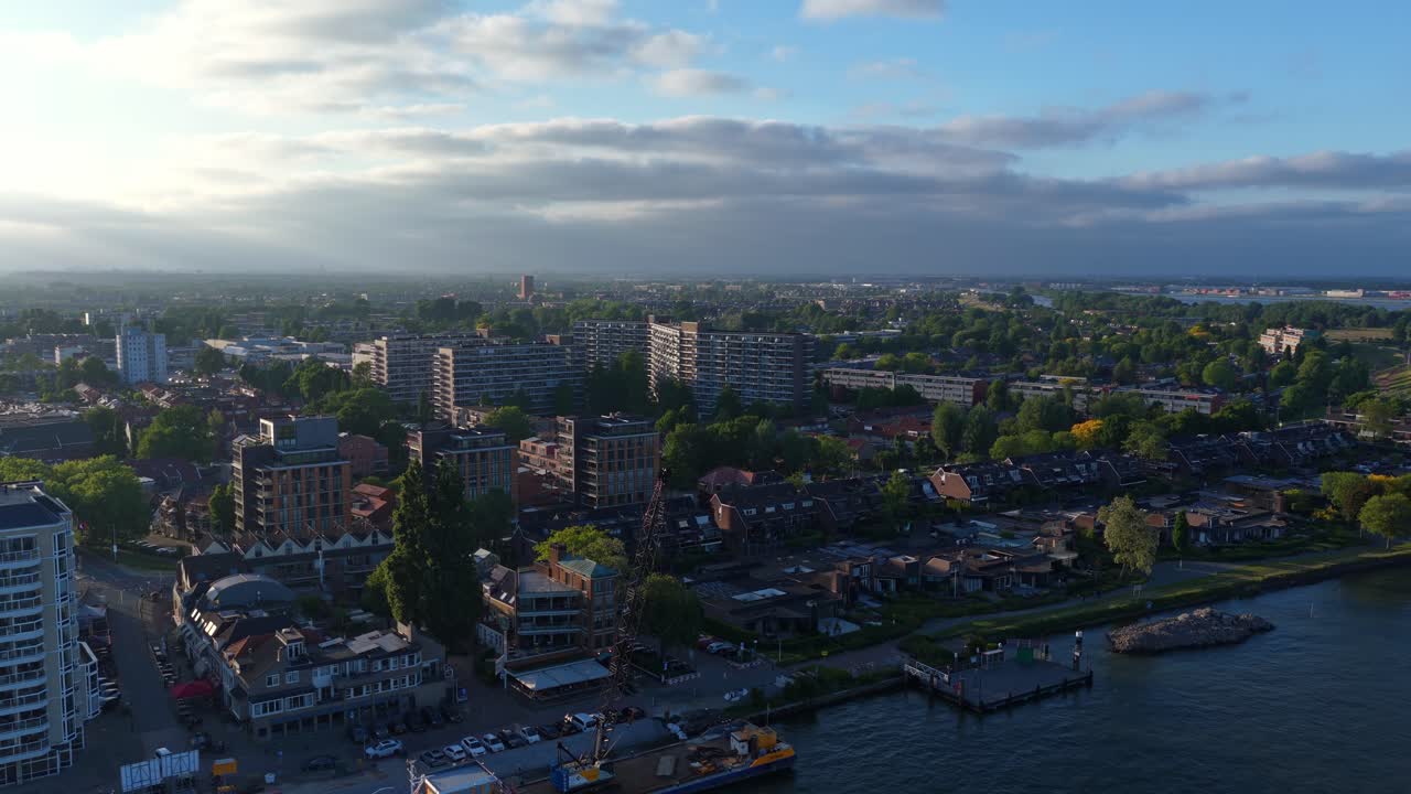 Drone shot over Dordrecht at sunrise showing residential buildings, canal, and moored boats near the quay