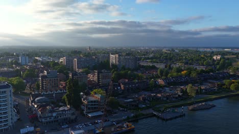 drone shot over dordrecht at sunrise showing residential buildings, canal, and moored boats near the quay