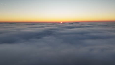 calming airplane view above clouds in atmosphere at sunset - orange horizon