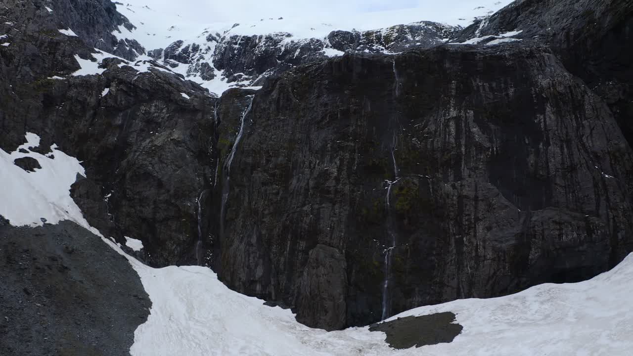 retiro aéreo de una montaña rocosa cubierta de nieve en fiordland, nueva zelanda, isla sur