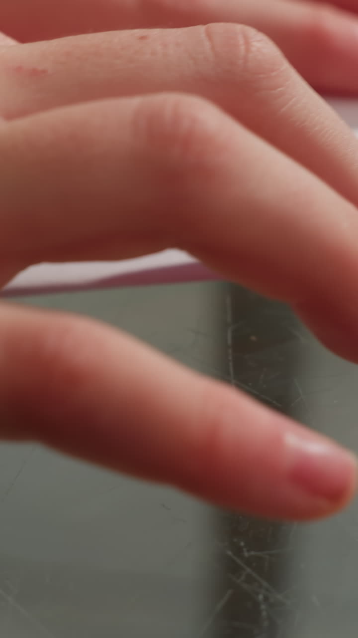 Detailed tactile craftsmanship, Focus on fingertips moistening and precise repetitive hand movements, Intimate shot capturing detailed hand actions during quiet paper finishing craft session