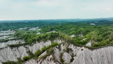 Cinematic-drone-shot-of-moonscape-badlands-with-green-plants-at-Tianliao-Moon-World-Park