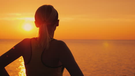 Atleta-Femenina-Intencionada-Mira-La-Atardecer-Sobre-La-Vista-Trasera-Del-Mar