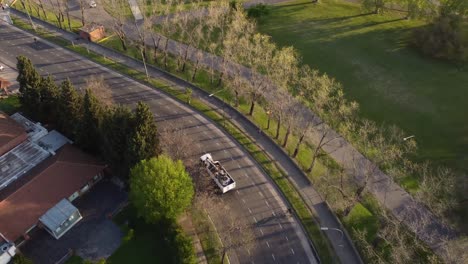 aerial tracking shot of scrap trash truck driving on rural road in buenos aires during sunset