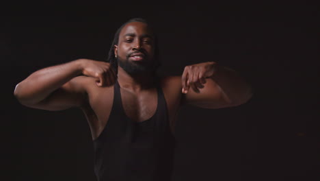 Portrait-Of-Serious-Male-Athlete-Wearing-Fitness-Vest-Training-Flexing-Muscles-And-Preparing-Psychologically-For-Sports-Event-Against-Black-Studio-Background-1