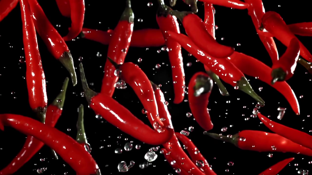 Fresh Red Chili Peppers and Water Droplets Falling in Slow Motion