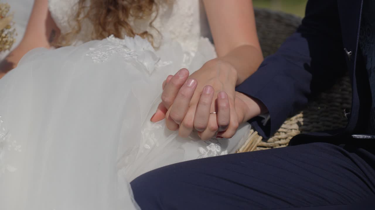 slowmotion shot of a newly married couple sitting down and holding hands