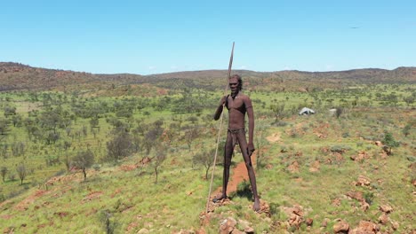 Excelente-Toma-Aérea-De-Una-Estatua-De-Un-Hombre-Aborigen-En-El-Campo-De-Aileron,-Australia