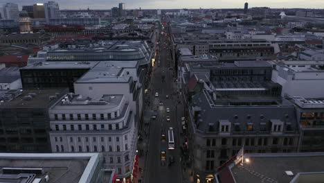 Traffic-in-long-straight-street-in-urban-borough.-Tilt-up-reveal-cityscape-and-cloudy-sky.-Dusk-in-city.-Berlin,-Germany