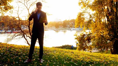 Businessman-talking-on-mobile-phone-and-holding-digital-tablet