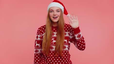 frau in weihnachtspullover winkt handpalme in hallo geste begrüßt jemanden, um das neue jahr zu feiern