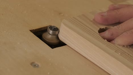 a carpenter uses a router tool for rounding the corner of the wood