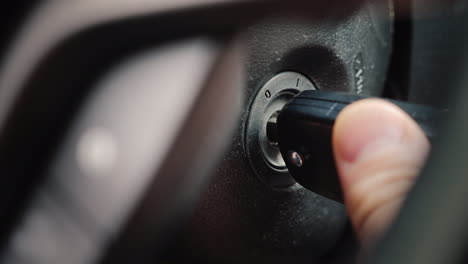 the ignition key is inserted into the well and start the car engine close-up shot