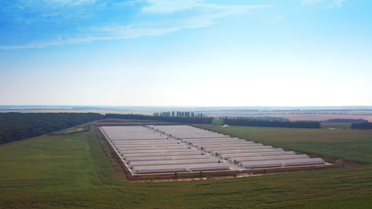 Endless beautiful landscapes of farmlands with modern farm at the foreground. Up-to-date warehouses for breeding domestic animals.