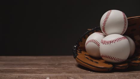 Cerrar-Estudio-De-Béisbol-Bodegón-Con-Pelotas-En-El-Guante-Del-Receptor-En-El-Piso-De-Madera-2