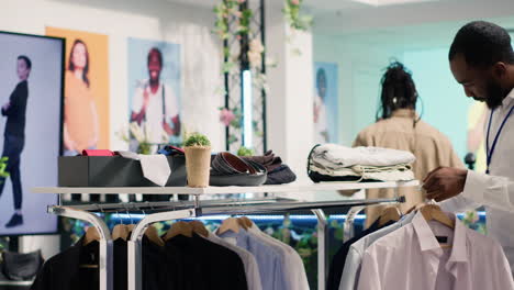 employee arranging shirts in sh shop