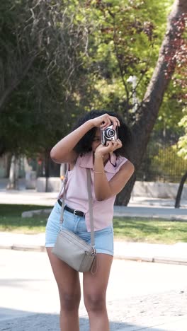 woman photographing anonymous friends with digital camera in sunny city
