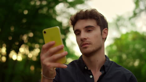 Retrato-De-Un-Hombre-Serio-Leyendo-Un-Mensaje-En-El-Teléfono-Móvil-Durante-Un-Paseo-Por-El-Parque