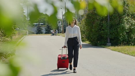 elegant baltic businesswoman with red suitcase walking in sunlight, slowmo traveling