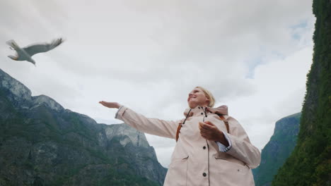 Eine-Frau-Füttert-Eine-Möwe,-Die-Im-Vertrauen-Fliegt-Und-Die-Konzeptreise-Durch-Die-Fjorde-Von-Nor-Zähmt