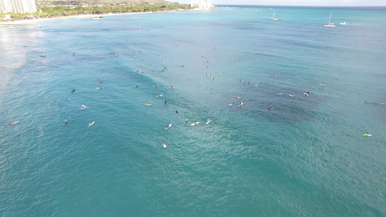 열대 섬의 인기 있는 서핑 장소에 줄을 선 서퍼들의 회전하는 4k 공중 드론 샷