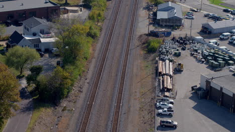 aerial view of train tracks in small town neighborhood with tilt up to follow the track to the horizon