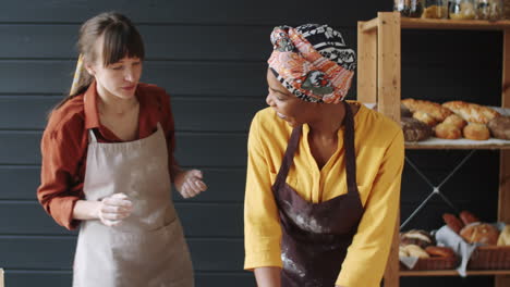 multiethnic female bakers kneading dough together and talking