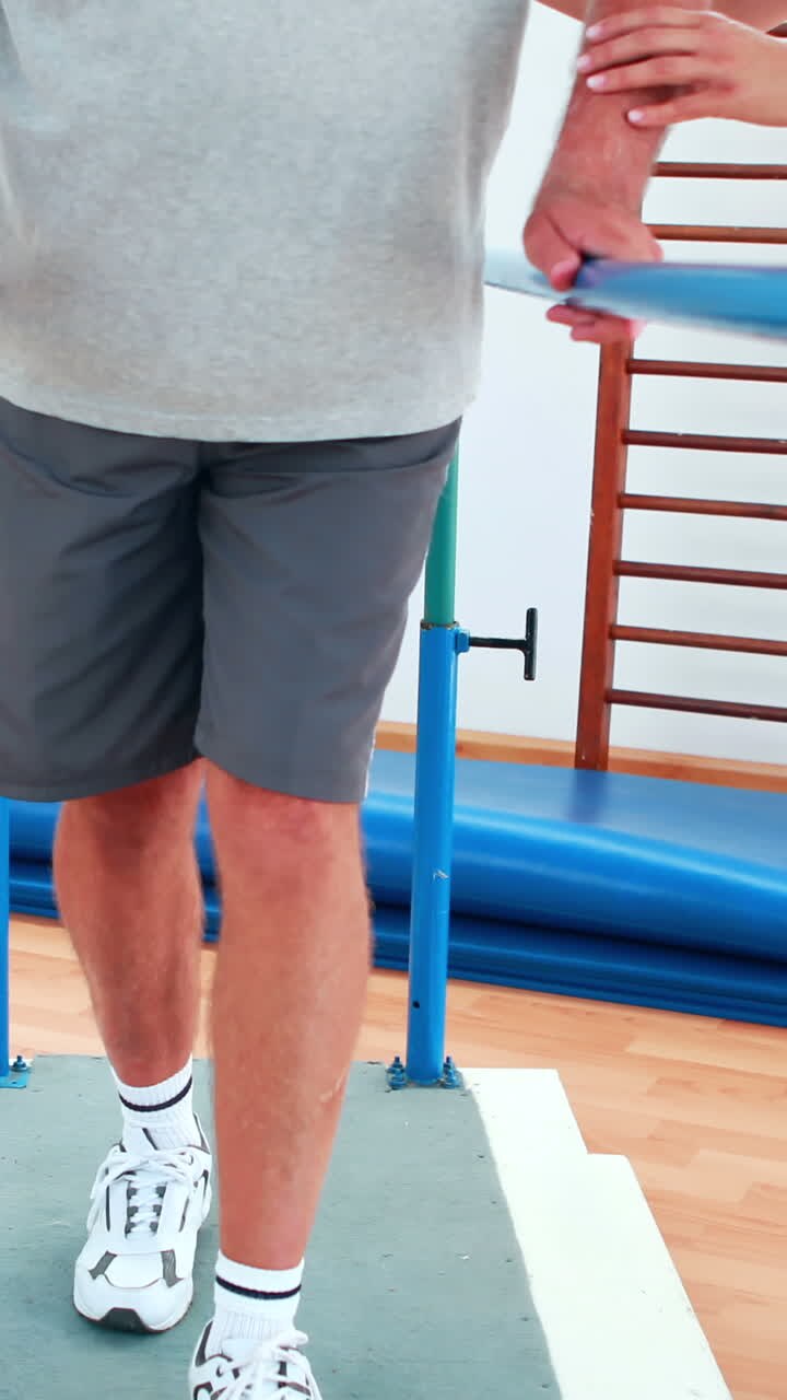 Physiotherapist helping patient walk with parallel bars