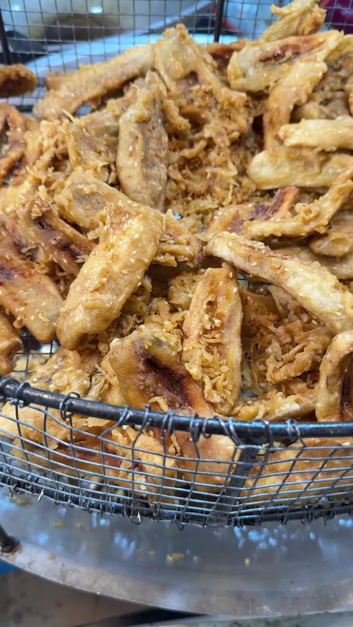 Frittelle di banana fritte che sgocciolano in un cestello di metallo
