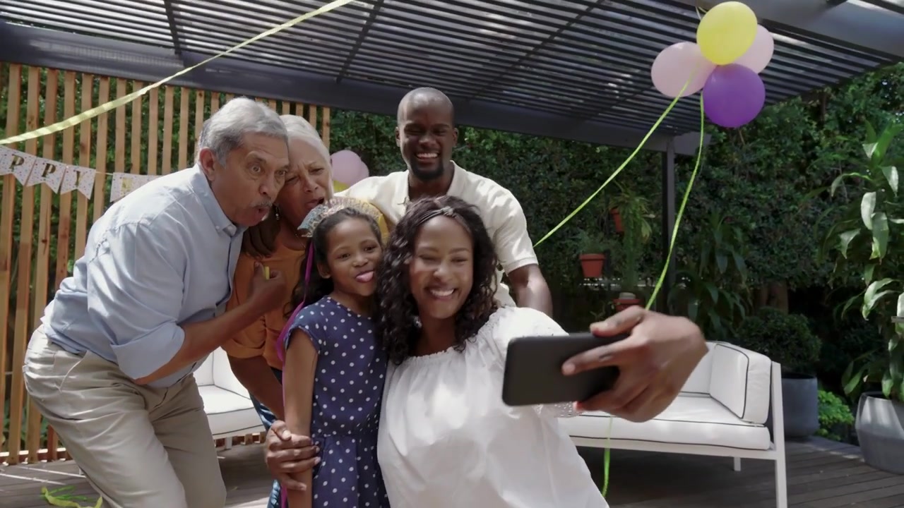 Woman kneeling holding phone initiating selfie on deck, AR beams radiating, family creating content