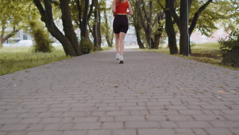 Back-view-of-athletic-fit-sport-jogger-teen-girl-training-marathon-run,-running-forward-on-road