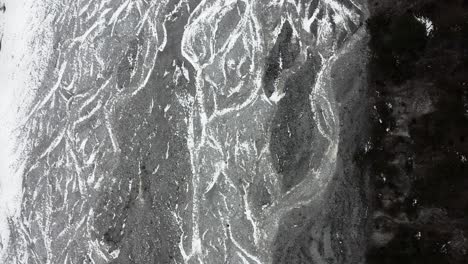 Aerial:-top-down-view-of-hiker-walking-on-Yulong-glacier-riverbed,-Yunnan-China