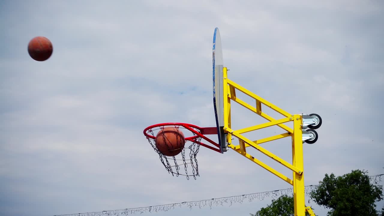 Pallacanestro da strada. La palla vola verso il canestro. Al rallentatore