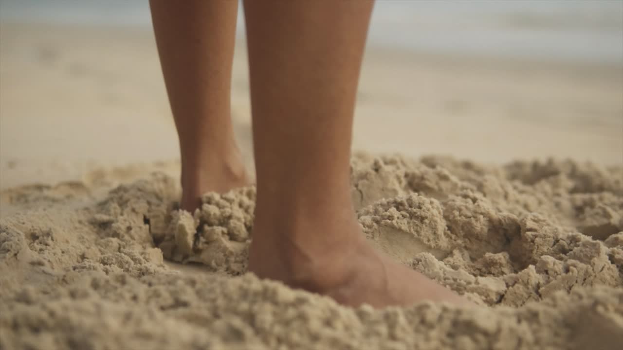 Cinematic slow motion shot of female feet moving through fine sand on the beach in Goa, India, Slomo