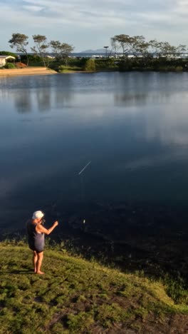 person fishing by a calm lake at sunset