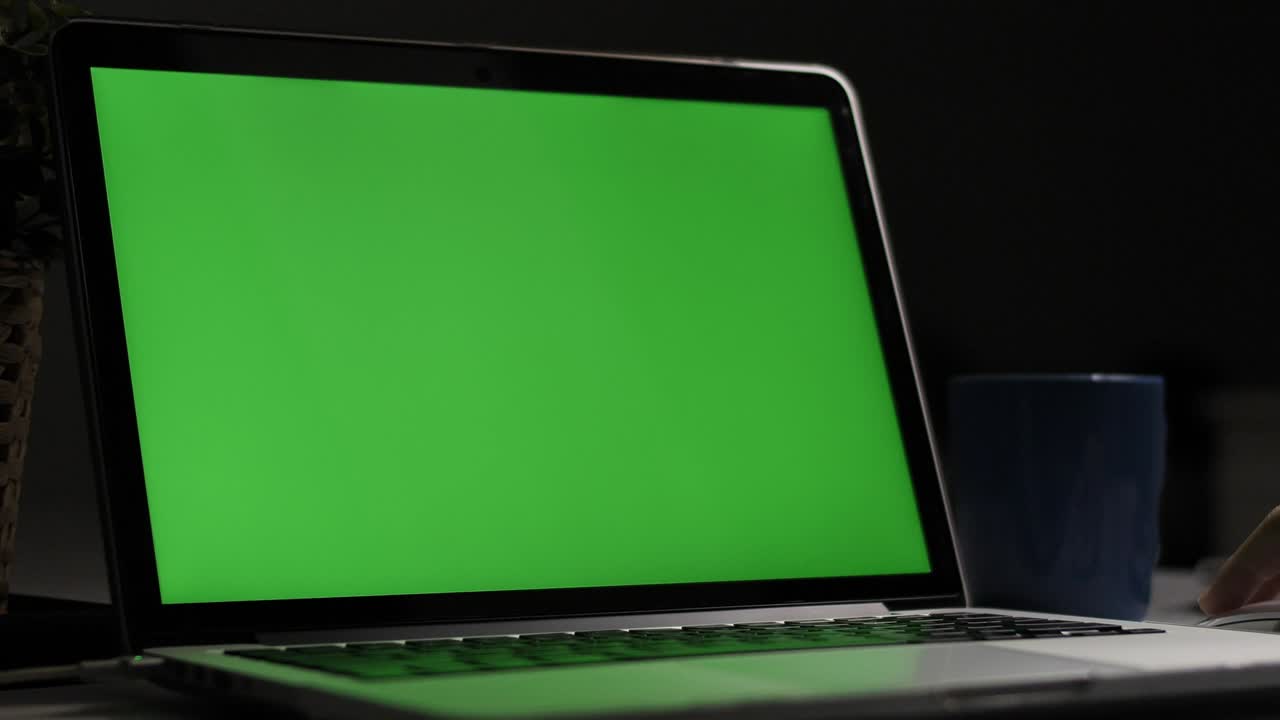 Over the shoulder shot of a young boy using on laptop computer on desk, looking at green screen. Dolly shoot 60fps.