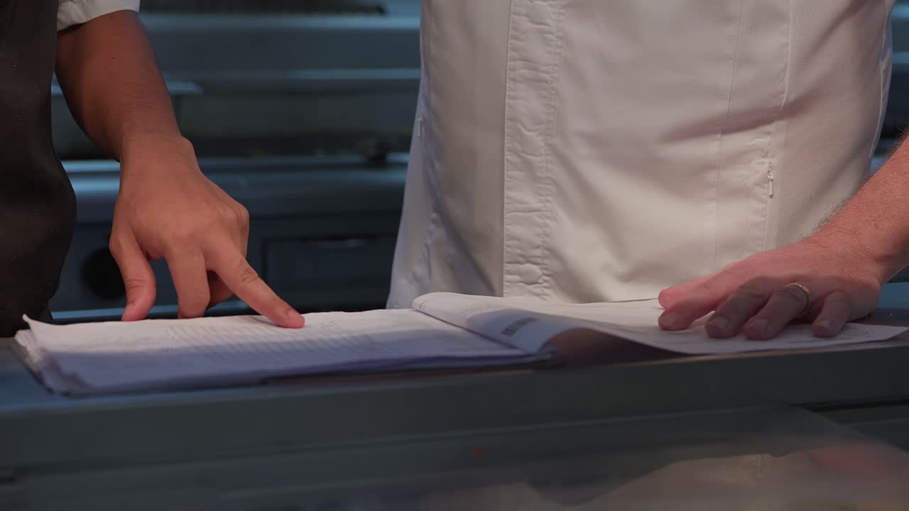 Chefs discussing the menu and reservations in the daily planning sheet, pointing to what needs to be prepared for the day