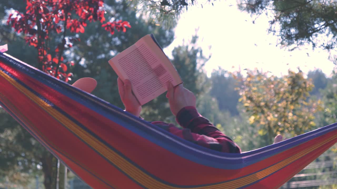 Woman relaxing in a hammock reading a book