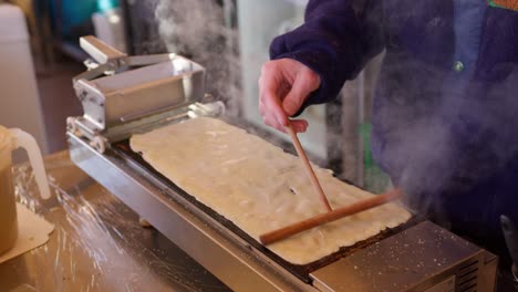 primer plano de una persona amasando panqueques tradicionales o masa de crepé en un plato caliente