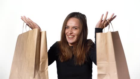 Positive human emotions. Pretty young woman with shopping bags after successful shopping, smiling and looking at the camera on a white background