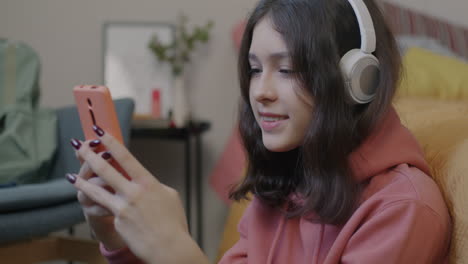 teenage girl using a smartphone while wearing headphones