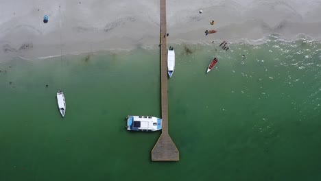 View-from-above-of-beach,pier-and-boats-close-to-shoreline-in-Coche-Island,-South-America