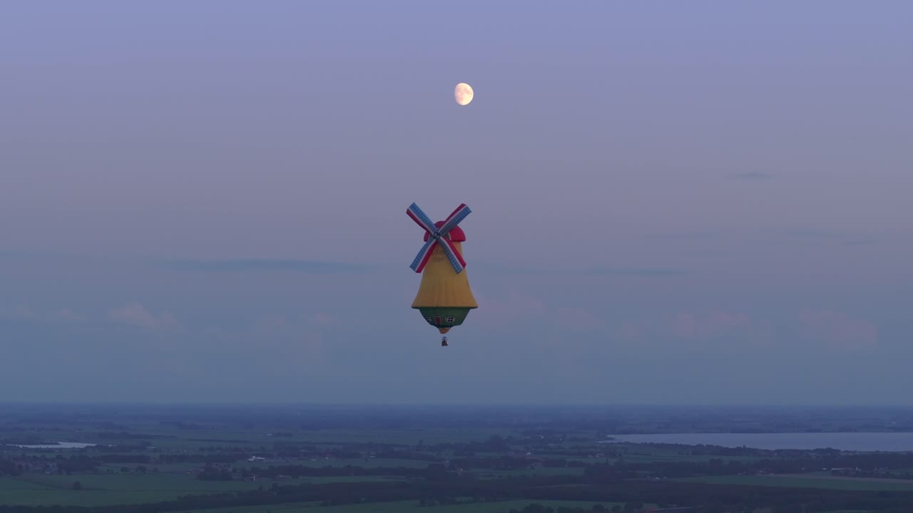 네덜란드 에서 해가 지는 동안 풍차 모양 의 다채로운 뜨거운 공기 풍선 을 공중 에서 볼 수 있다