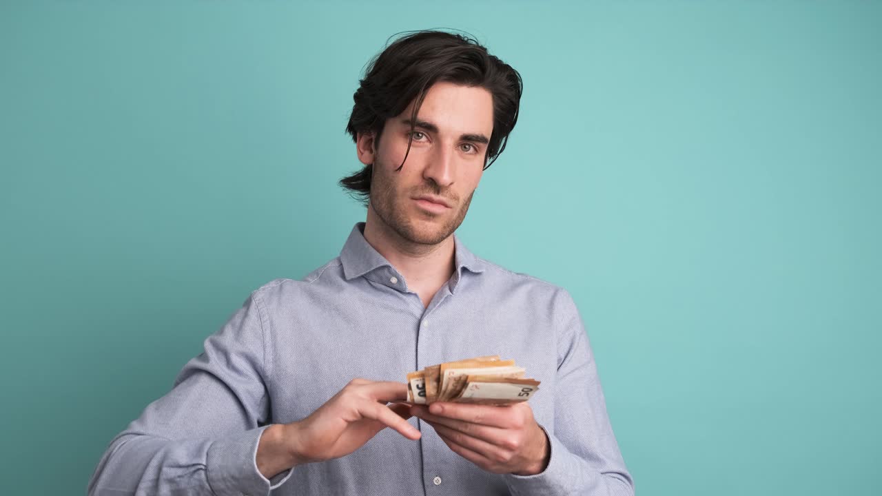 Cheerful rich man throwing around cash in blue studio