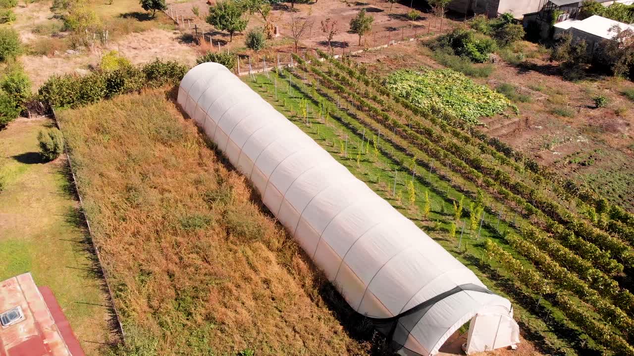imágenes aéreas de drones orbitando alrededor del invernadero de plástico en el jardín