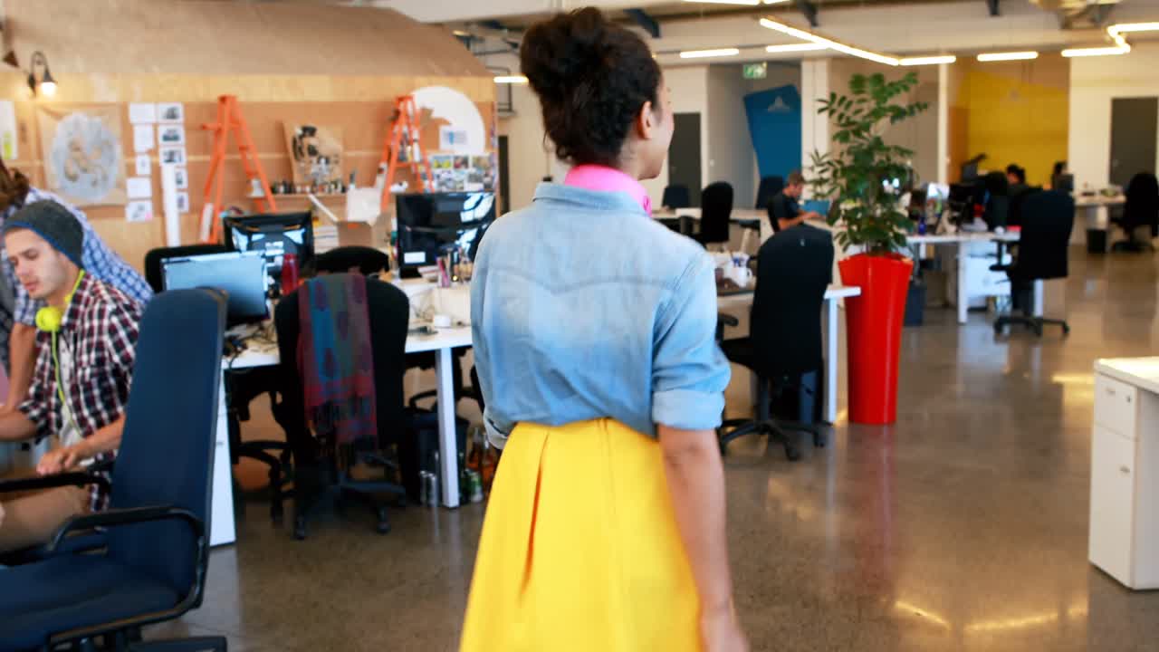 Empresária caminhando enquanto colegas de trabalho trabalham