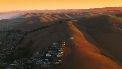 lovely cozy city at the foot of the mountains. stunning panorama of bare hills in the beams of setting sun. aerial view.